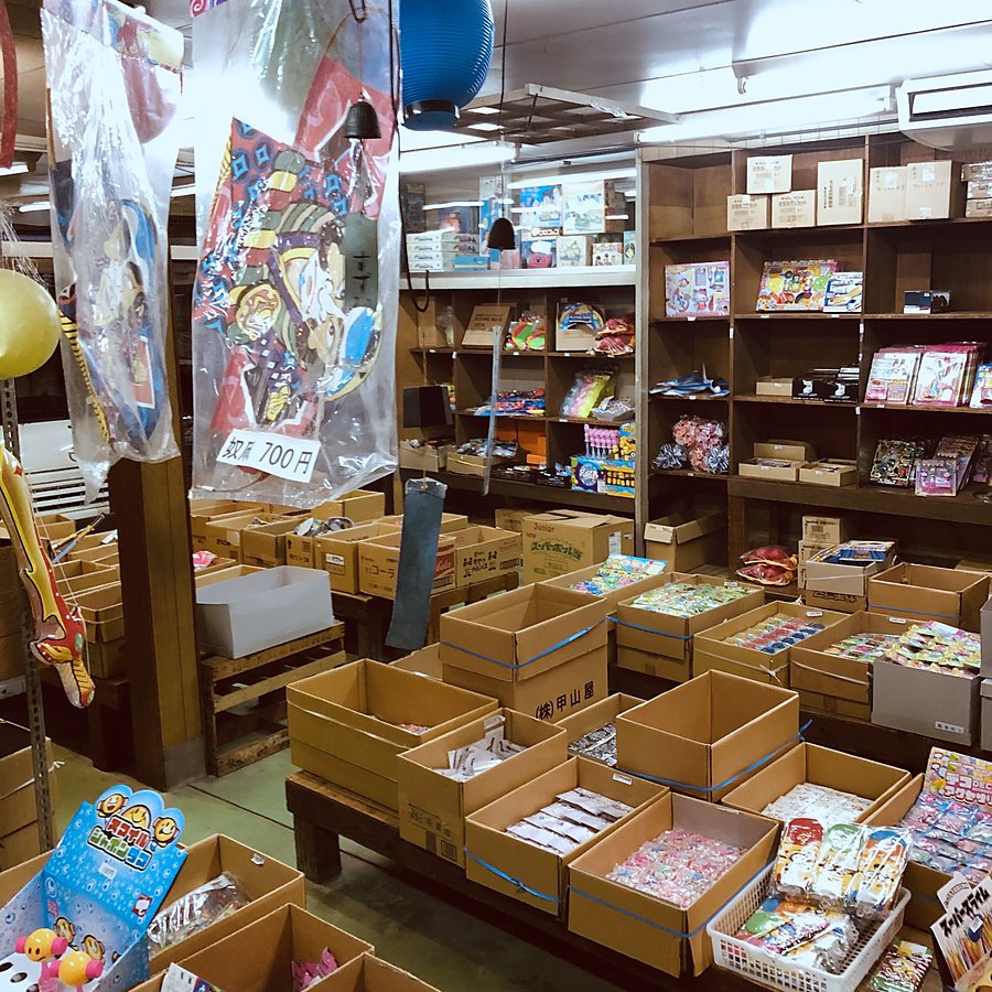 提灯が下がる店内。箱に入ったままの駄菓子やおもちゃが並ぶ